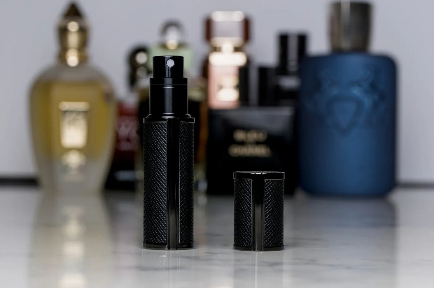 Flâneur Parfum leather travel atomizer on marble surface with luxury fragrance collection in background