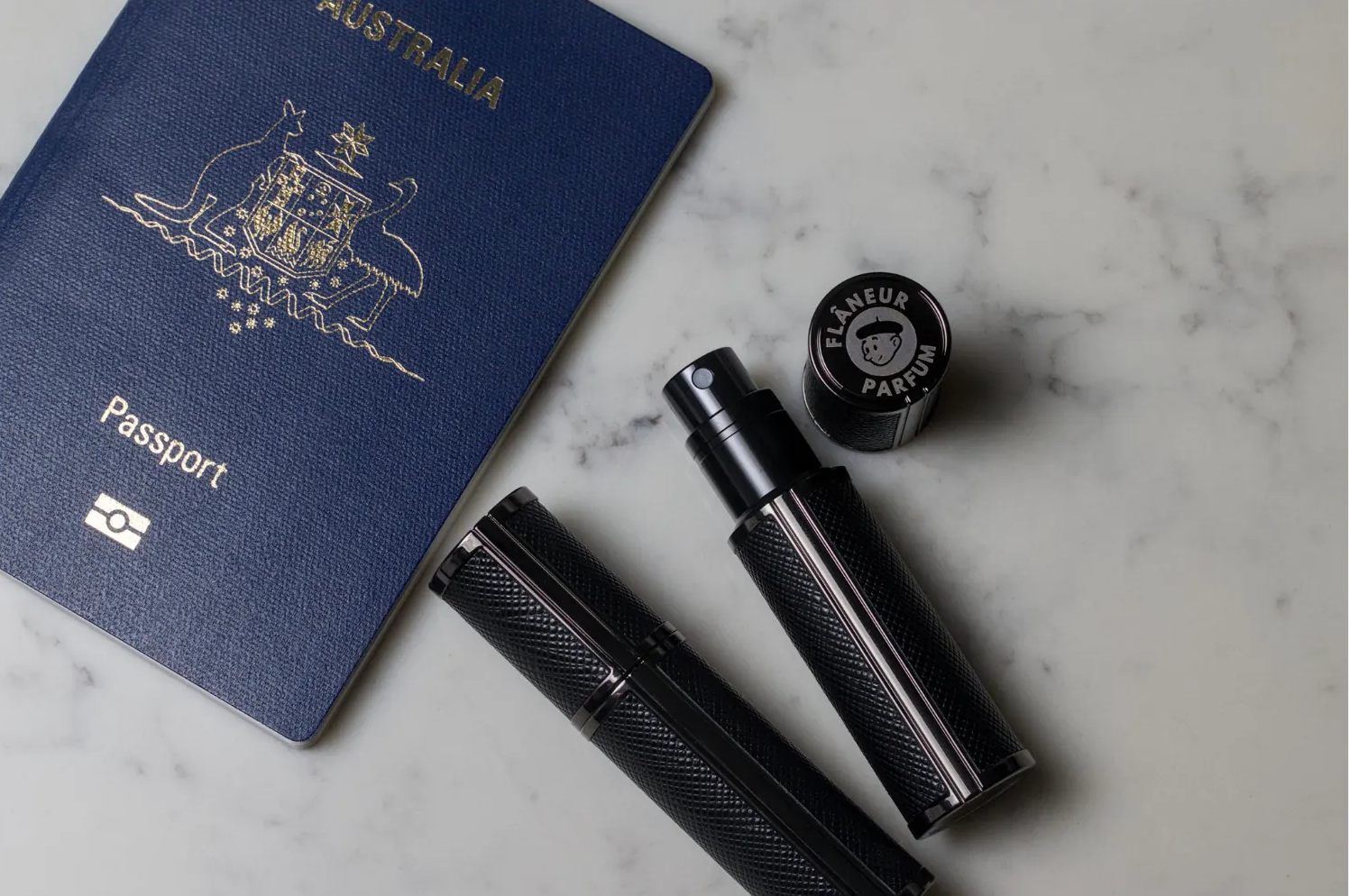Flâneur Parfum leather travel atomizers with Australian passport on marble surface showing engraved brand logo cap
