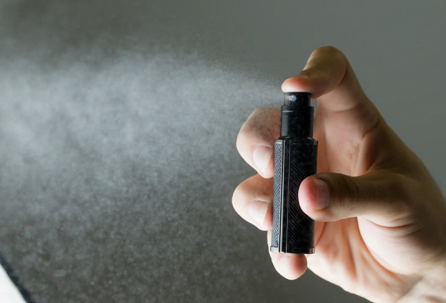 Hand holding Flâneur Parfum leather travel atomizer spraying ultra fine fragrance mist