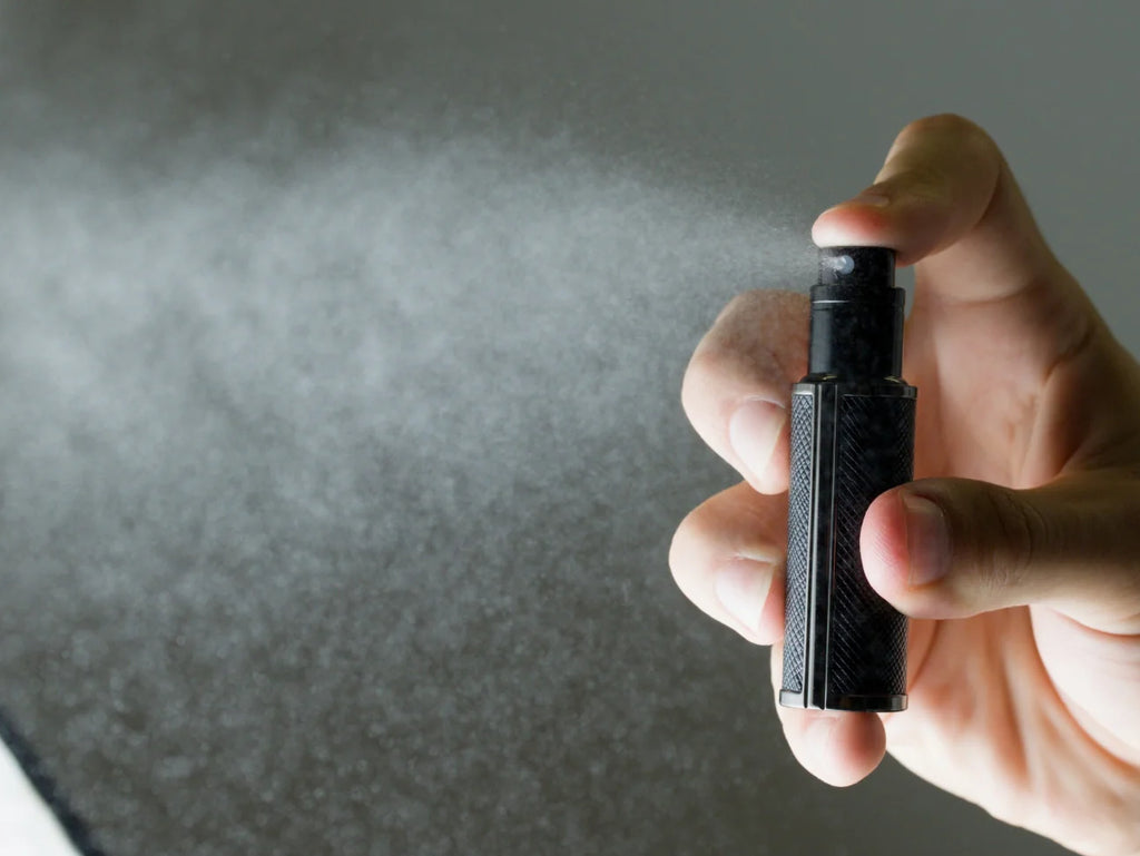 Hand holding Flâneur Parfum leather travel atomizer spraying ultra fine fragrance mist